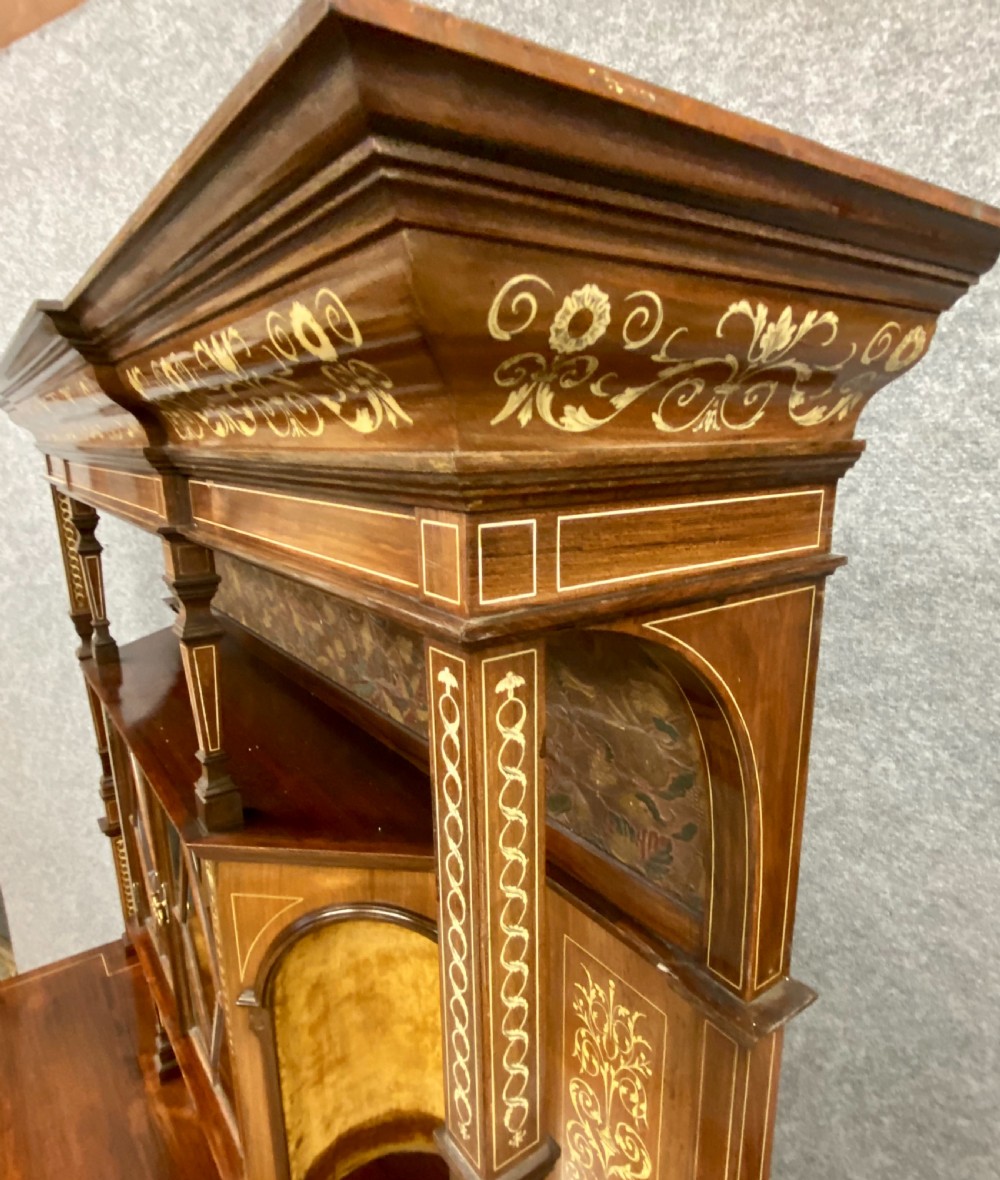 An Aesthetic Movement dark wood side cabinet featuring detailed marquetry inlays, an elevated superstructure with a central glazed cabinet, open niches, a mirror, a single drawer, and lower shelf spaces. View XIX