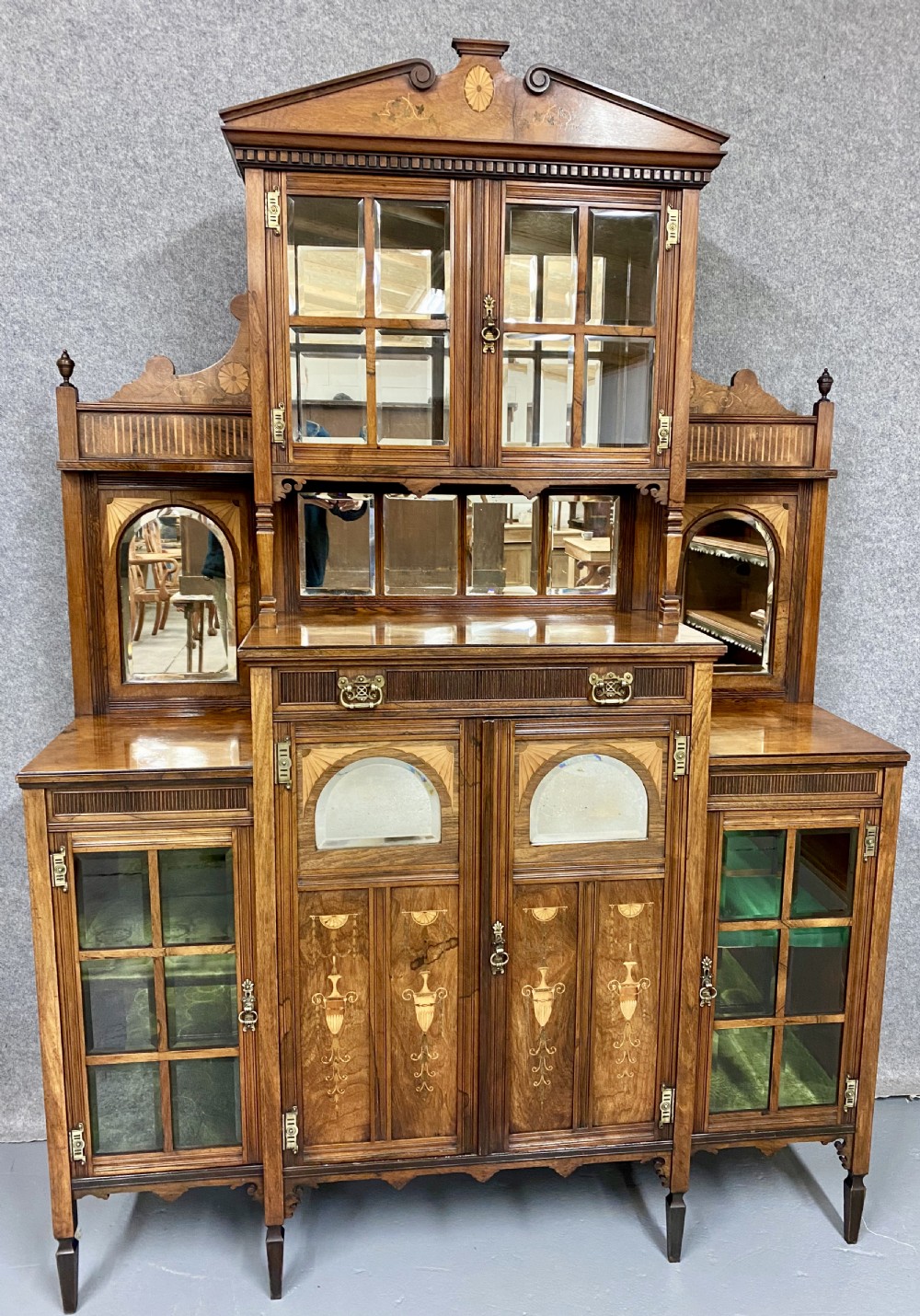An antique inlaid rosewood side cabinet featuring glazed doors, mirrored inset panels, classical marquetry urn motifs, and a pediment top. View II