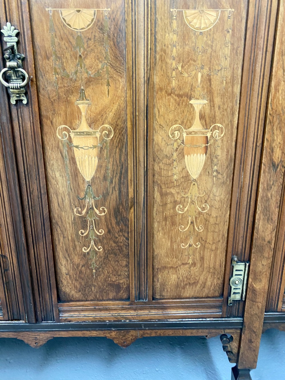 An antique inlaid rosewood side cabinet featuring glazed doors, mirrored inset panels, classical marquetry urn motifs, and a pediment top. View III