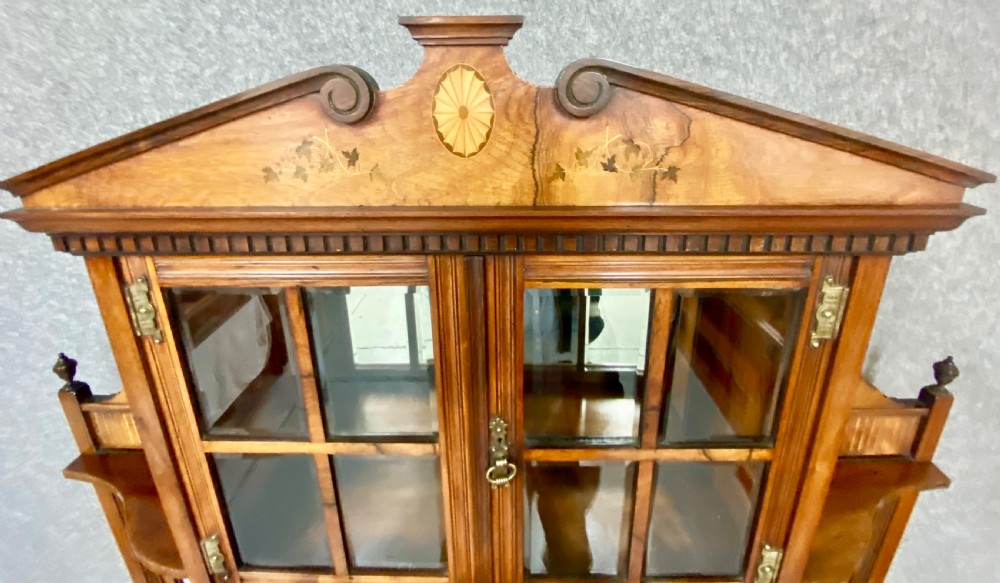 An antique inlaid rosewood side cabinet featuring glazed doors, mirrored inset panels, classical marquetry urn motifs, and a pediment top. View V