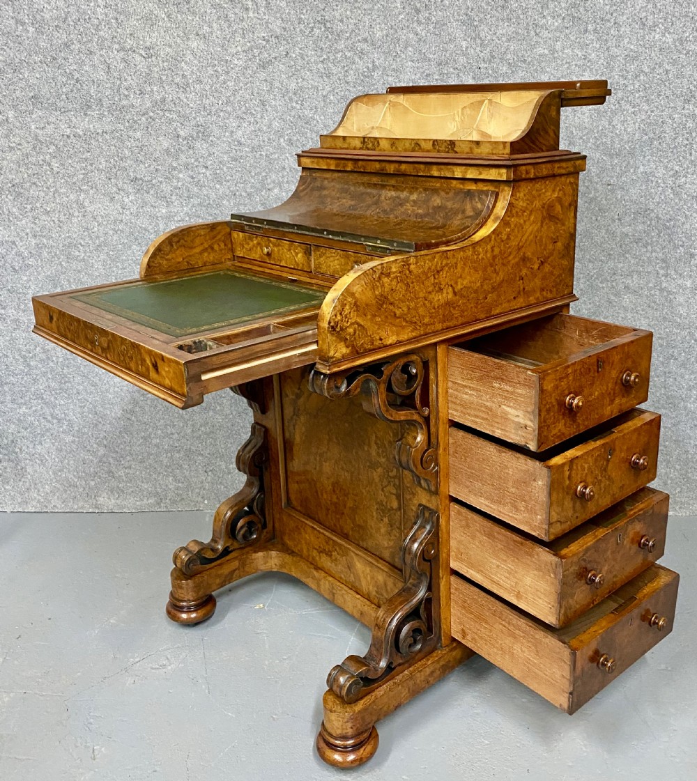 A Victorian burr walnut pop-up davenport desk featuring carved scroll supports, side drawers with wooden knobs, and a curved writing slope. View III
