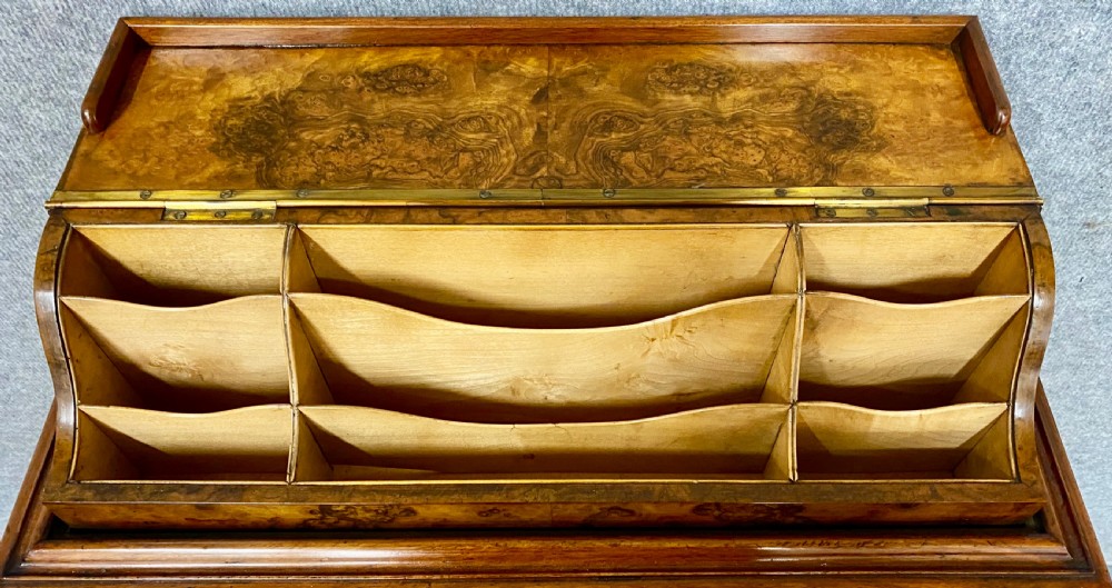 A Victorian burr walnut pop-up davenport desk featuring carved scroll supports, side drawers with wooden knobs, and a curved writing slope. View V