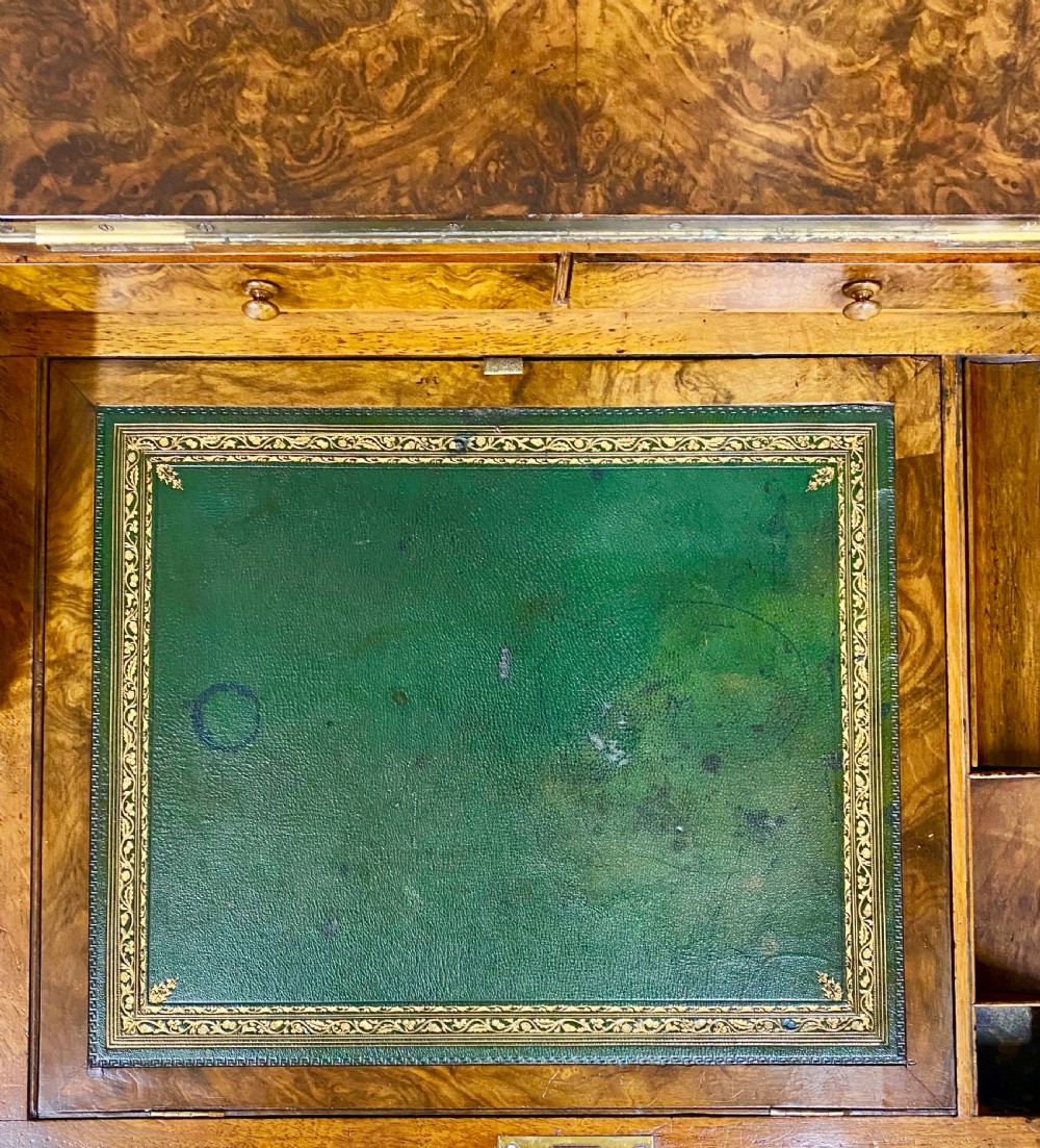 A Victorian burr walnut pop-up davenport desk featuring carved scroll supports, side drawers with wooden knobs, and a curved writing slope. View VI