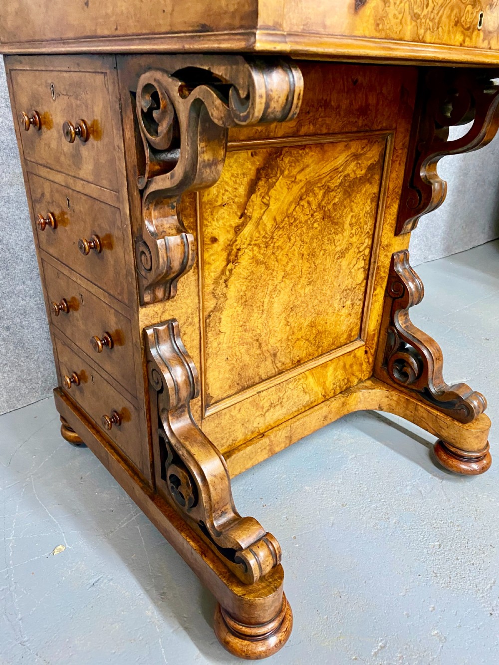A Victorian burr walnut pop-up davenport desk featuring carved scroll supports, side drawers with wooden knobs, and a curved writing slope. View VIII