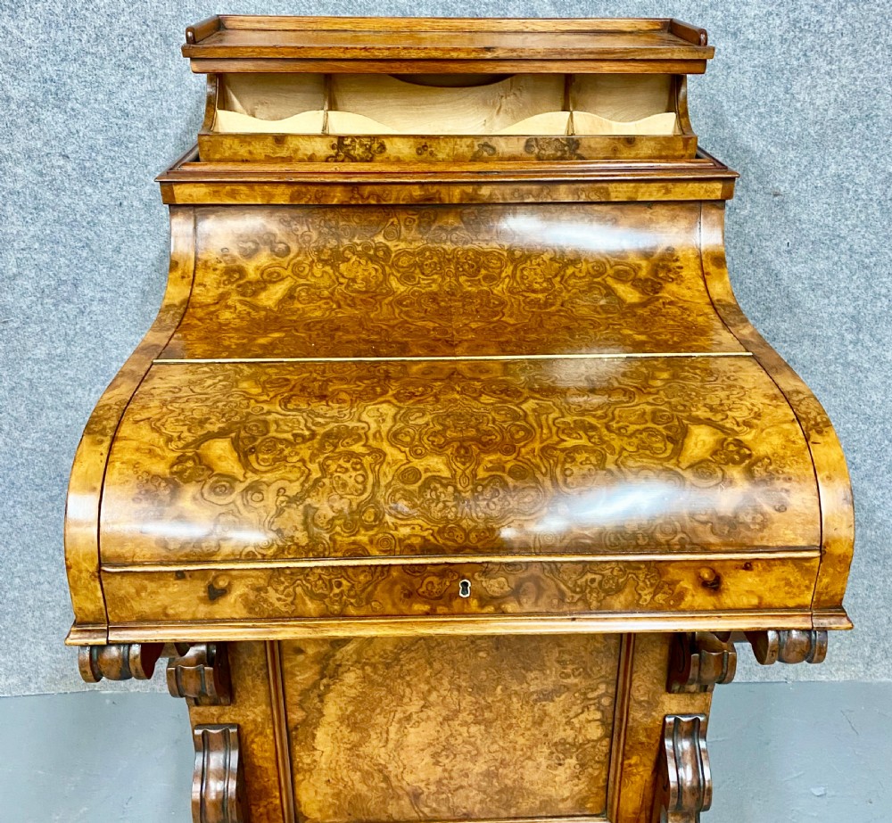 A Victorian burr walnut pop-up davenport desk featuring carved scroll supports, side drawers with wooden knobs, and a curved writing slope. View XII