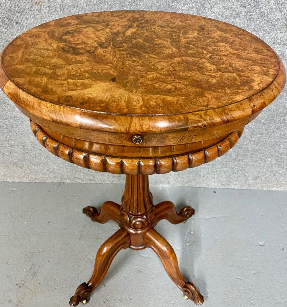An antique Victorian burr walnut tea poy featuring gadrooned detail around the basin, a fluted central pedestal column, and carved scroll feet on castors. View II