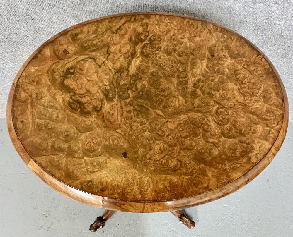 An antique Victorian burr walnut tea poy featuring gadrooned detail around the basin, a fluted central pedestal column, and carved scroll feet on castors. View III