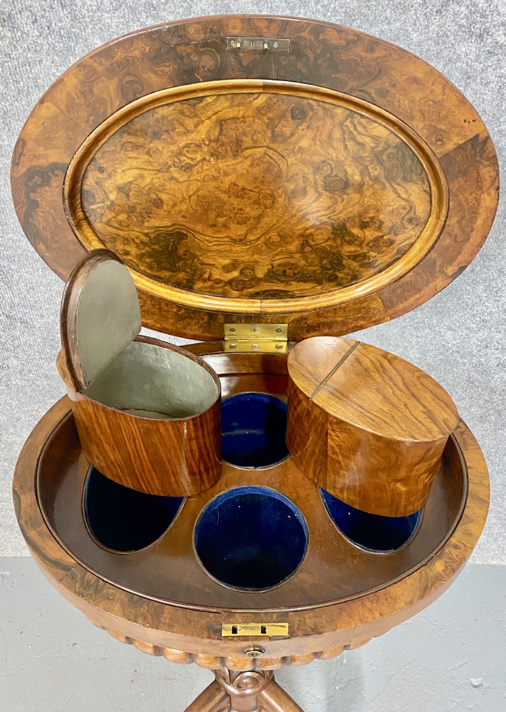 An antique Victorian burr walnut tea poy featuring gadrooned detail around the basin, a fluted central pedestal column, and carved scroll feet on castors. View IV
