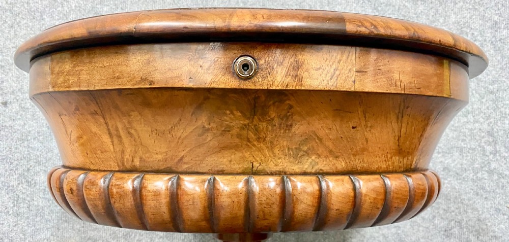 An antique Victorian burr walnut tea poy featuring gadrooned detail around the basin, a fluted central pedestal column, and carved scroll feet on castors. View VI