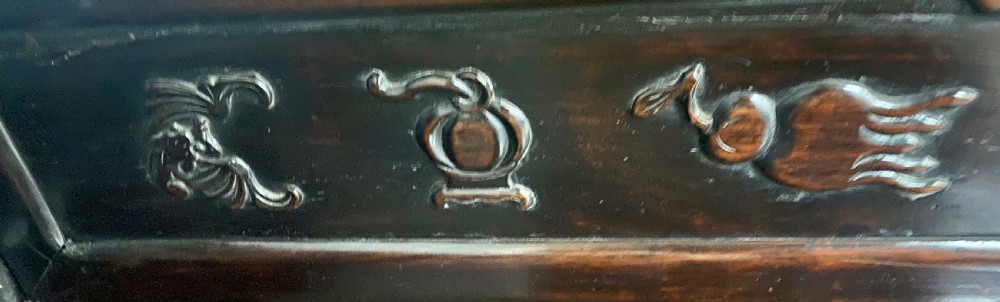 A dark hardwood Chinese bench featuring relief carved back panels depicting scholars objects, low side armrests, and an intricate apron with key fret motifs. View VIII