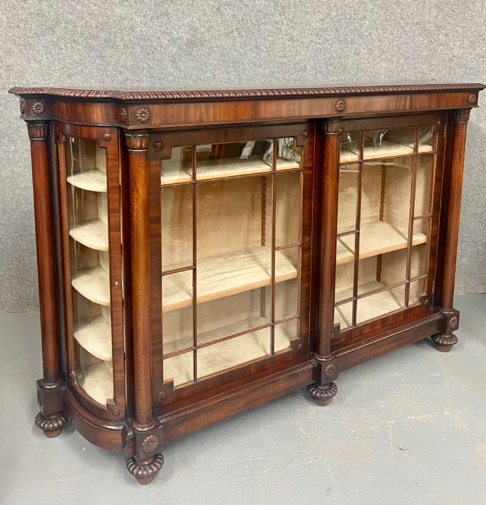 A nineteenth-century mahogany side cabinet featuring reeded columns, carved rosettes, gadrooned feet, and glazed doors.