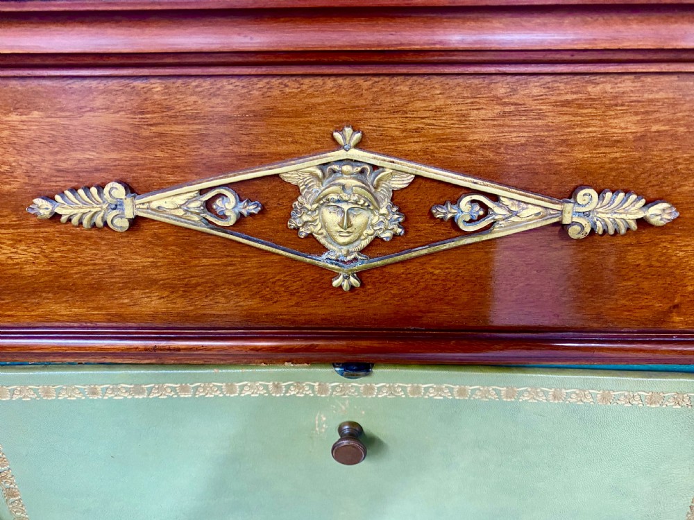 A pair of tall mahogany French Empire cartonnier chests featuring eight green gold-tooled leather drawers flanked by gilt ormolu mounts and terminal figures. View V