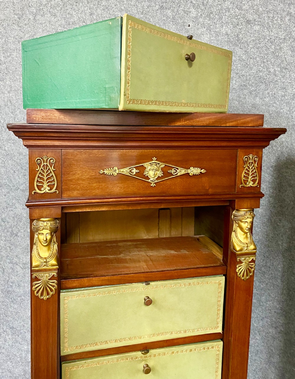 A pair of tall mahogany French Empire cartonnier chests featuring eight green gold-tooled leather drawers flanked by gilt ormolu mounts and terminal figures. View XIV