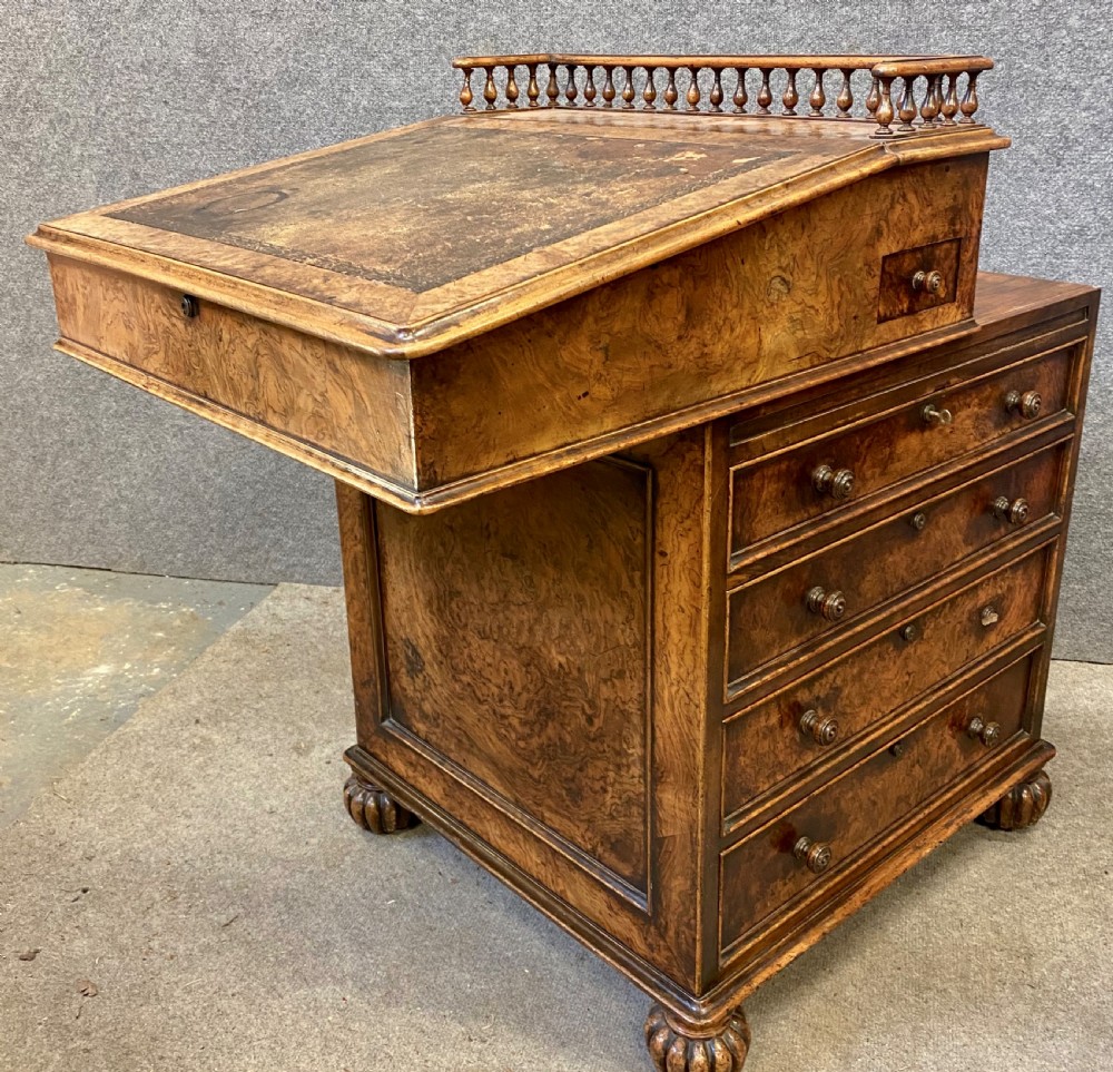 A compact burr walnut Davenport desk featuring an inclined leather writing slope, a spindled gallery top, and side drawers with turned knobs. View VIII