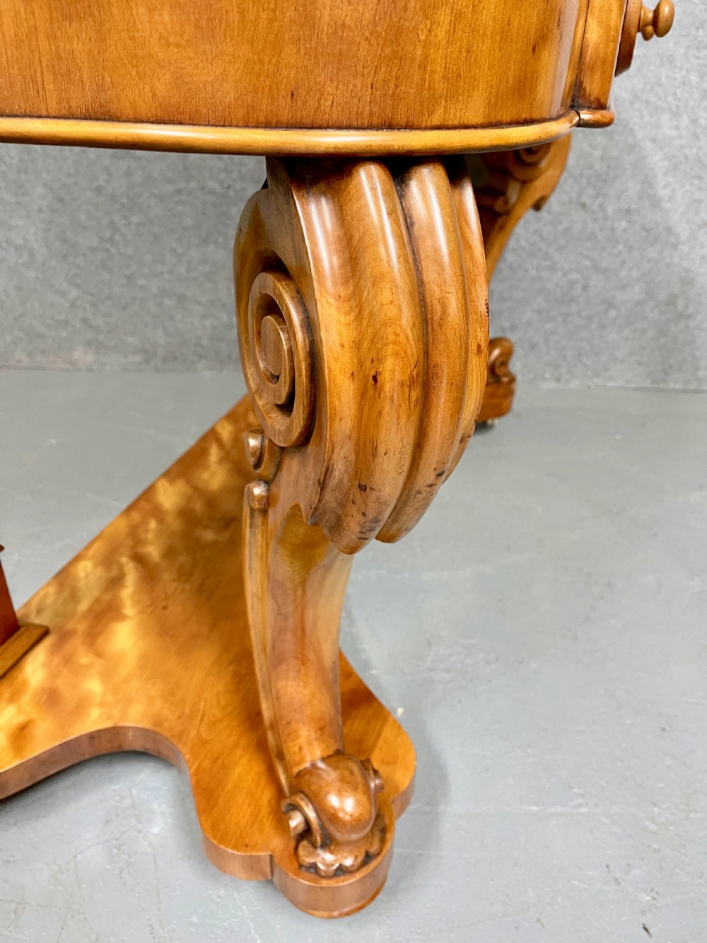 A Victorian Duchess dressing table in golden brown wood featuring an oval swivelling mirror, small raised drawers, a central frieze drawer, scroll carved front legs, and a plinth base. View VI