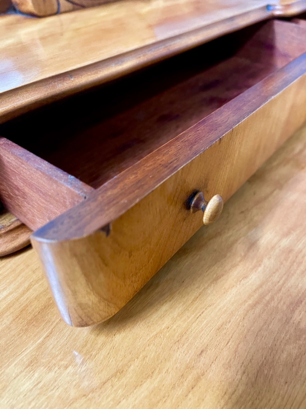 A Victorian Duchess dressing table in golden brown wood featuring an oval swivelling mirror, small raised drawers, a central frieze drawer, scroll carved front legs, and a plinth base. View VIII
