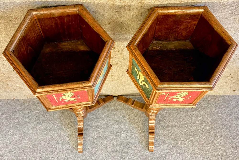 A pair of oak medieval style plant stands featuring hexagonal needlepoint tops decorated with fleur-de-lis and lion heraldic motifs on barley twist stems with tripod bases. View VII