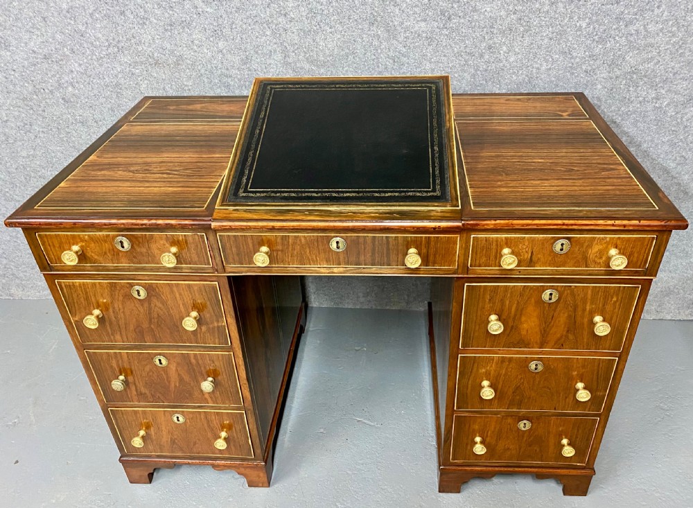 A Regency mahogany pedestal partners desk featuring a central green leather inset writing surface, brass knob handles, and stringing inlay. View II