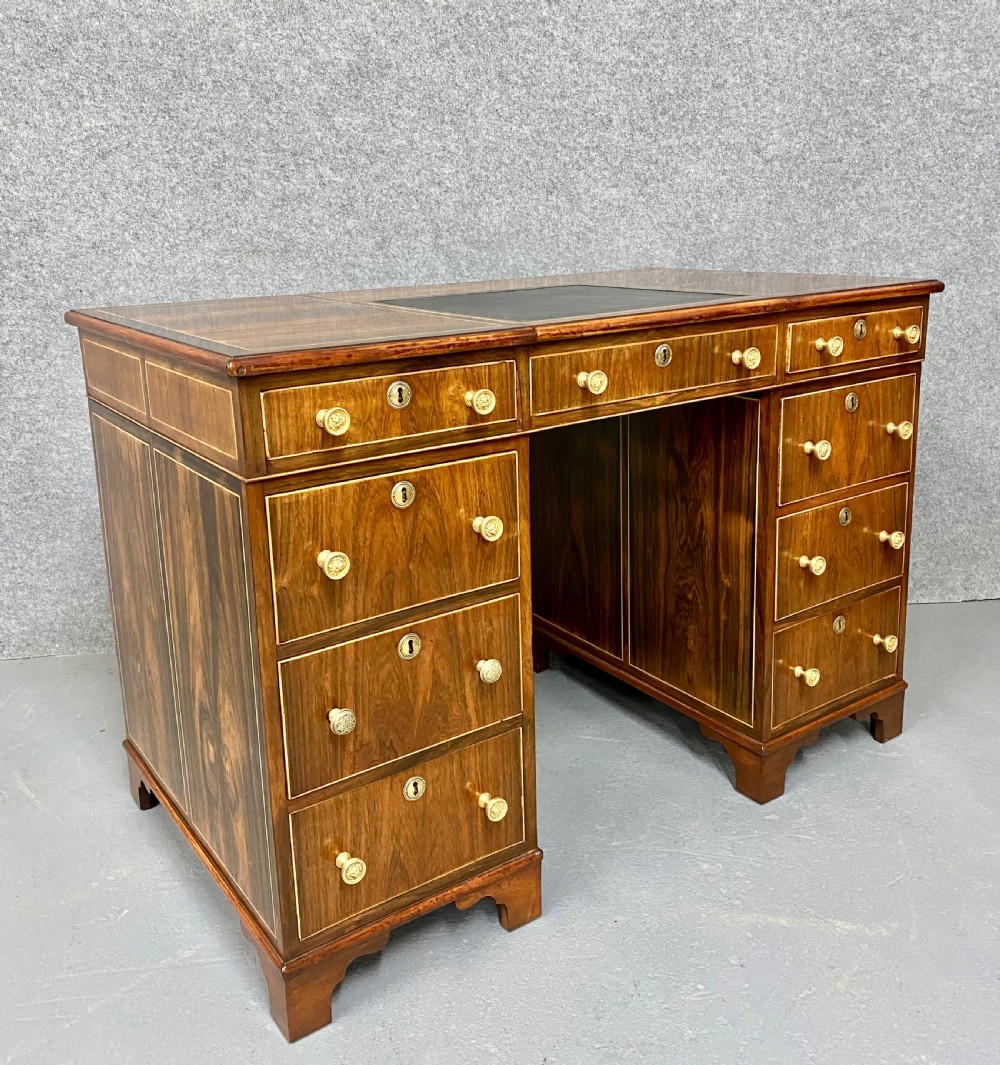 A Regency mahogany pedestal partners desk featuring a central green leather inset writing surface, brass knob handles, and stringing inlay. View III