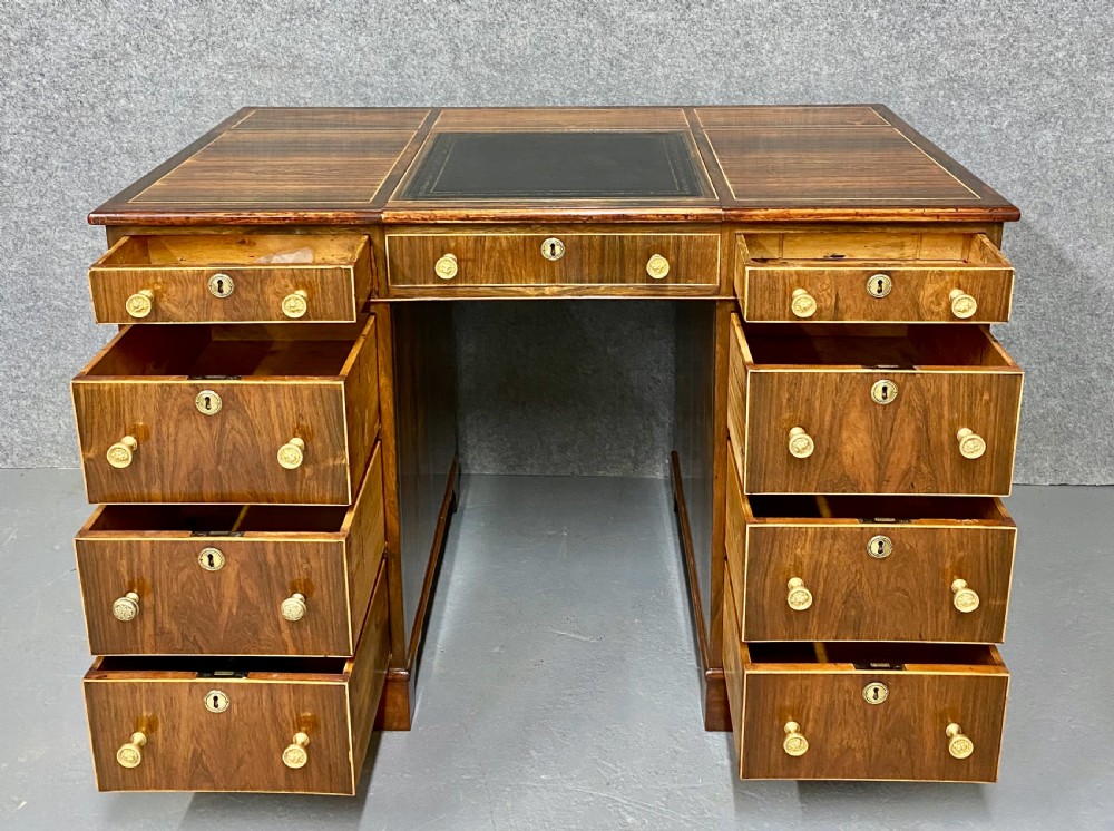 A Regency mahogany pedestal partners desk featuring a central green leather inset writing surface, brass knob handles, and stringing inlay. View V