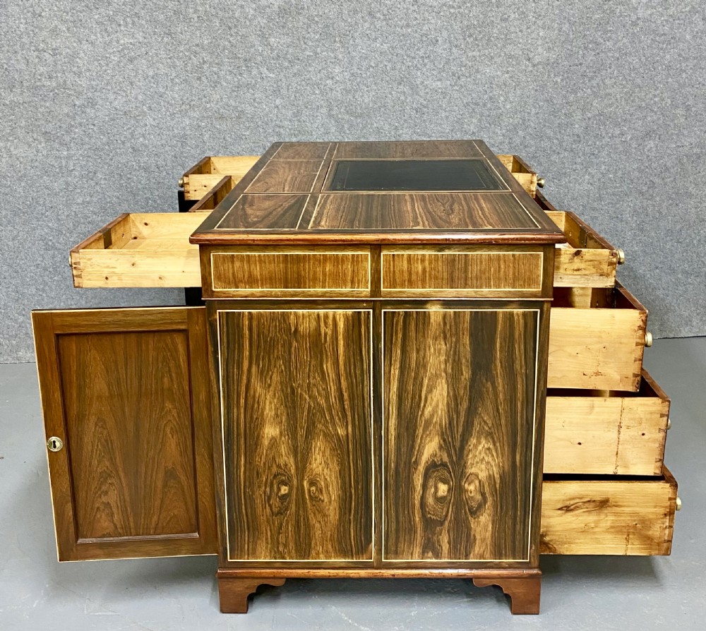 A Regency mahogany pedestal partners desk featuring a central green leather inset writing surface, brass knob handles, and stringing inlay. View VI