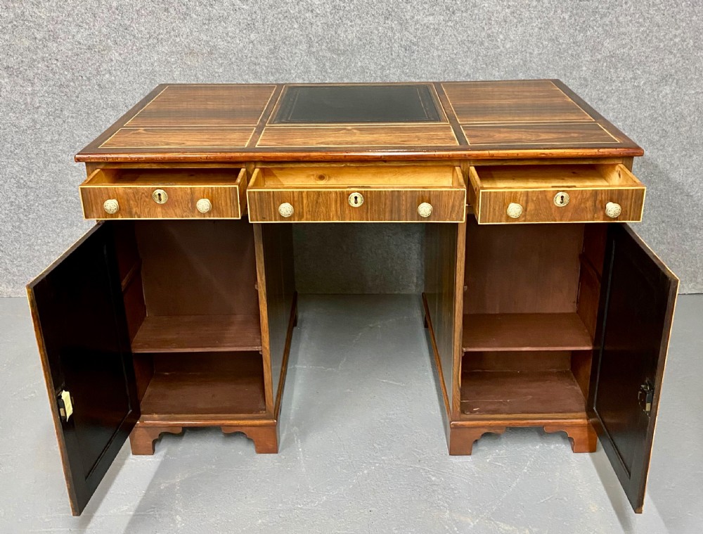 A Regency mahogany pedestal partners desk featuring a central green leather inset writing surface, brass knob handles, and stringing inlay. View VIII