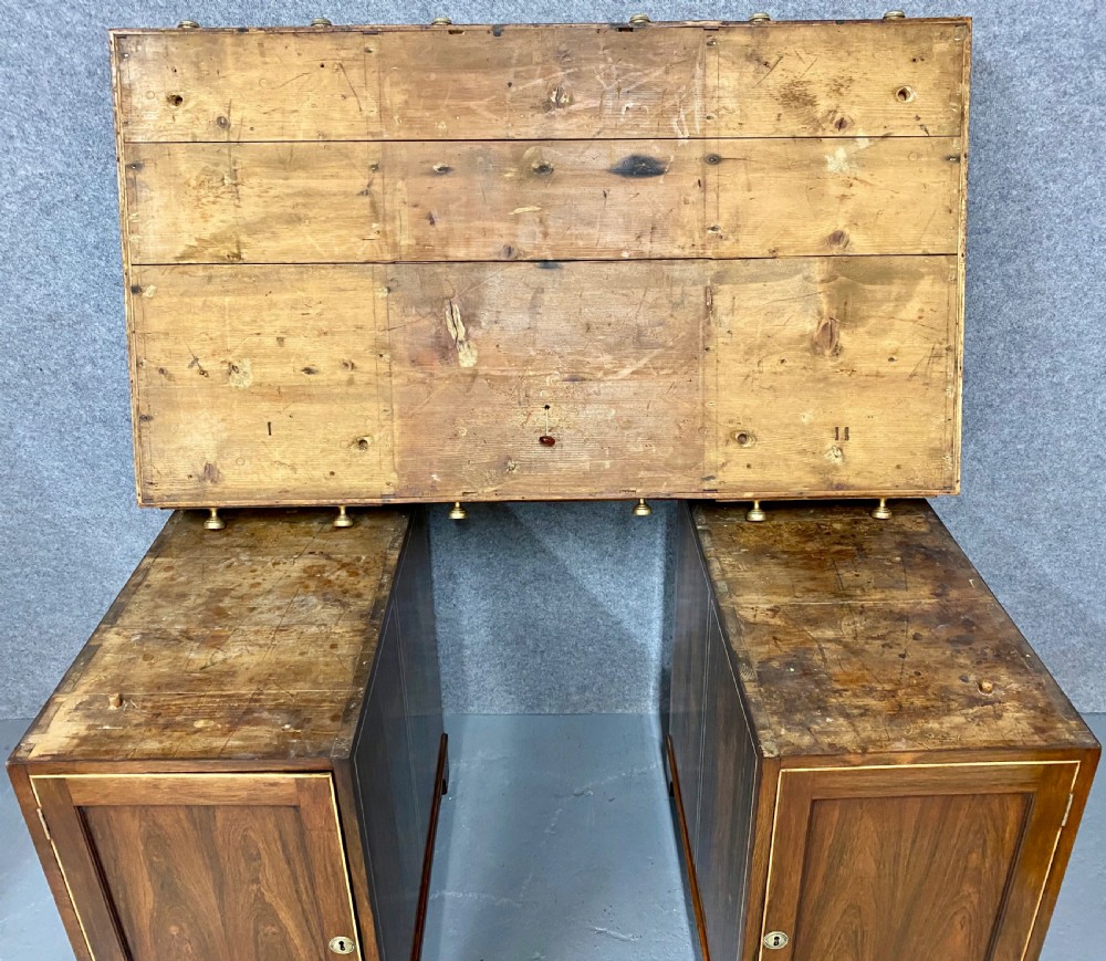 A Regency mahogany pedestal partners desk featuring a central green leather inset writing surface, brass knob handles, and stringing inlay. View X