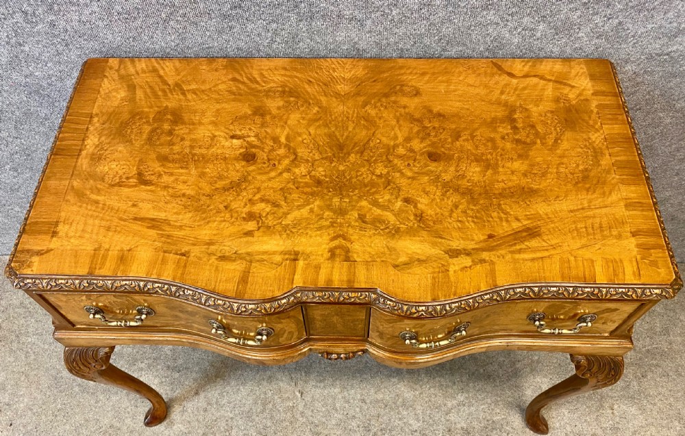 A nine-piece Queen Anne style dining room suite featuring a burr walnut dining table, matching sideboards, and red patterned fabric chairs with cabriole legs. View VI