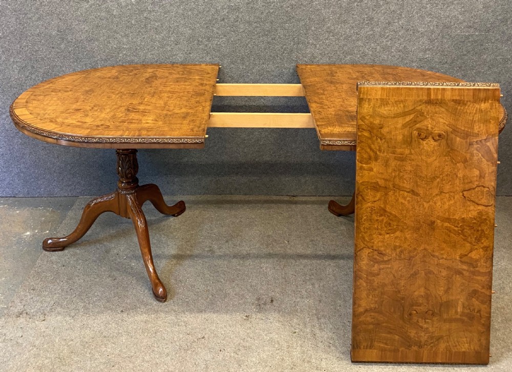A nine-piece Queen Anne style dining room suite featuring a burr walnut dining table, matching sideboards, and red patterned fabric chairs with cabriole legs. View IX