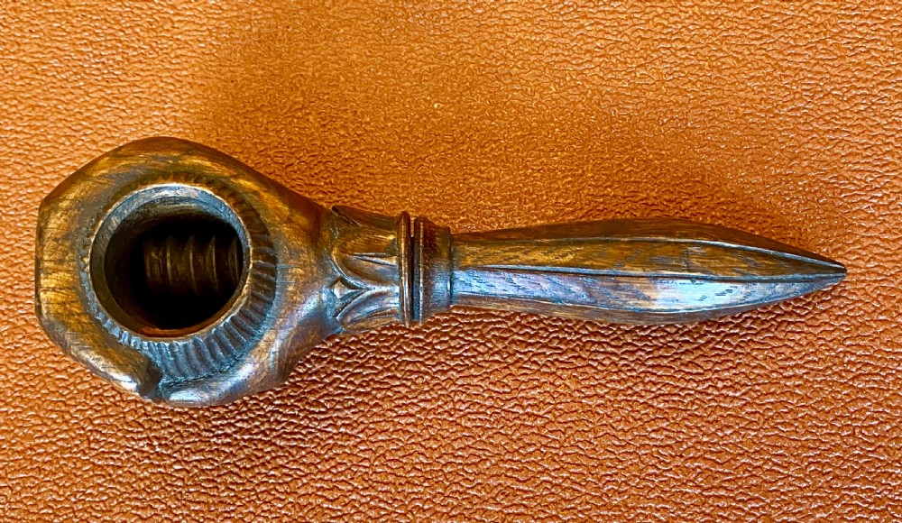 An antique hand-carved wooden treen nutcracker shaped as a human fist clasping a textured ball, resting atop a faceted handle. View IV