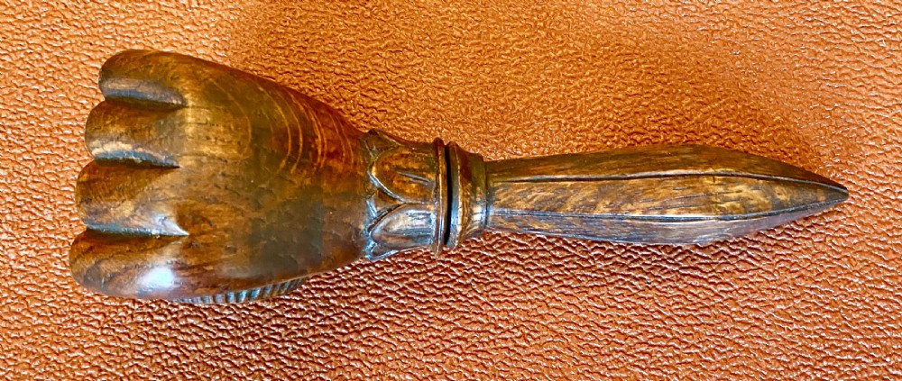 An antique hand-carved wooden treen nutcracker shaped as a human fist clasping a textured ball, resting atop a faceted handle. View V