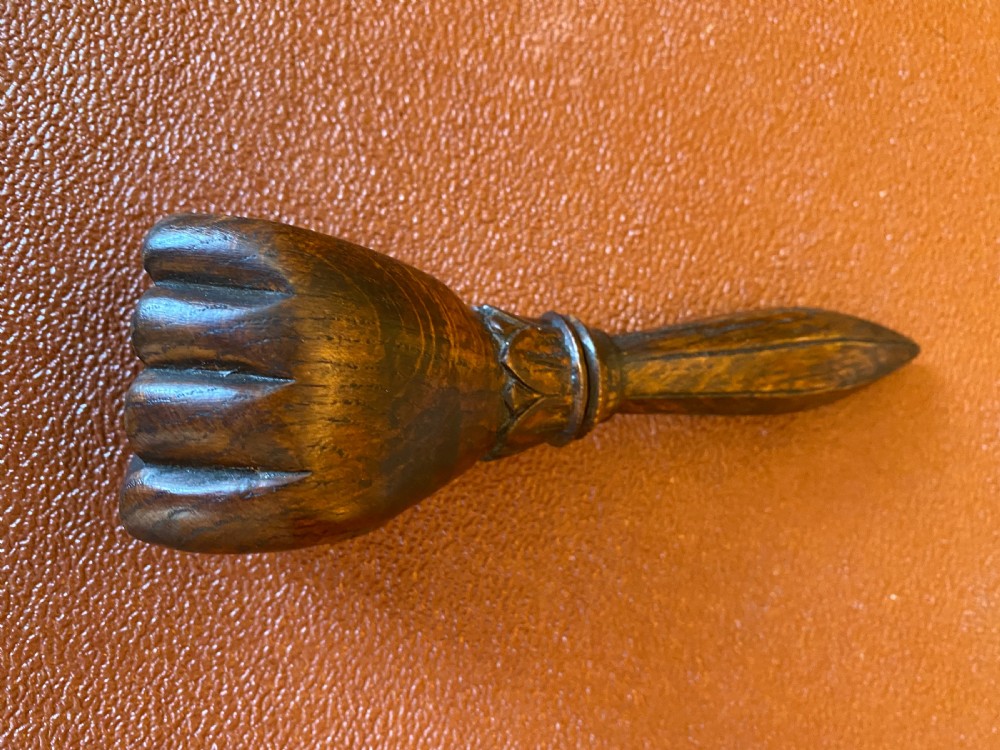 An antique hand-carved wooden treen nutcracker shaped as a human fist clasping a textured ball, resting atop a faceted handle. View VI