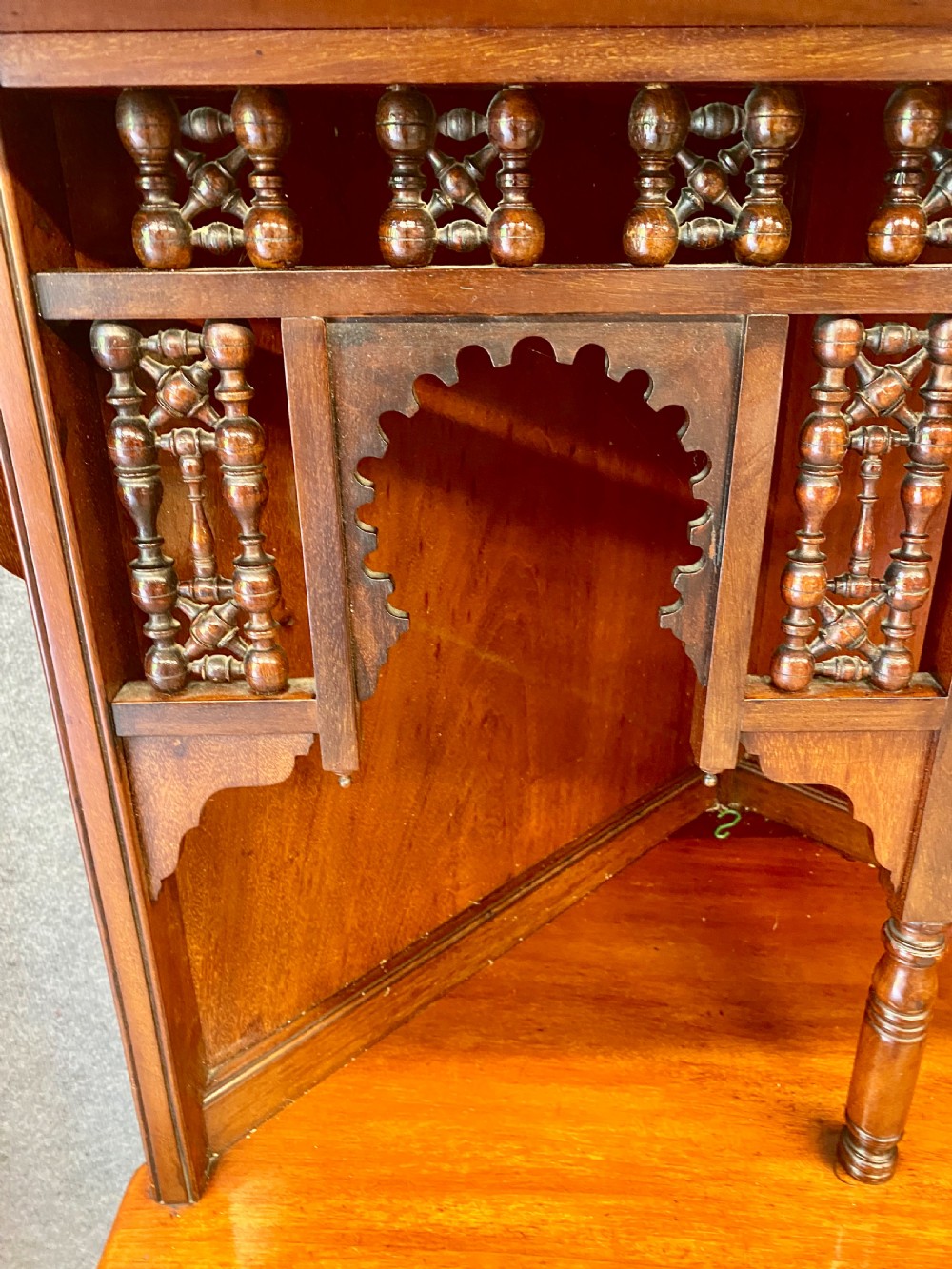 A late nineteenth-century Anglo-Moorish tiered wooden corner cabinet featuring mashrabiya fretwork, horseshoe arches, starburst door panels, and two drawers with brass pulls. View II