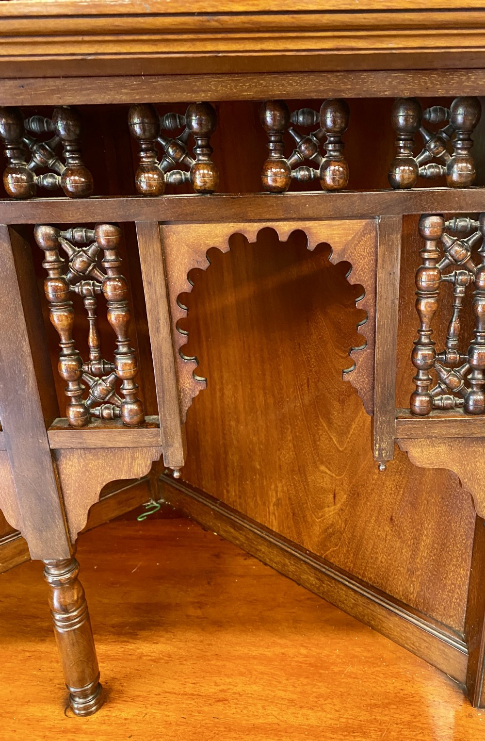 A late nineteenth-century Anglo-Moorish tiered wooden corner cabinet featuring mashrabiya fretwork, horseshoe arches, starburst door panels, and two drawers with brass pulls. View III