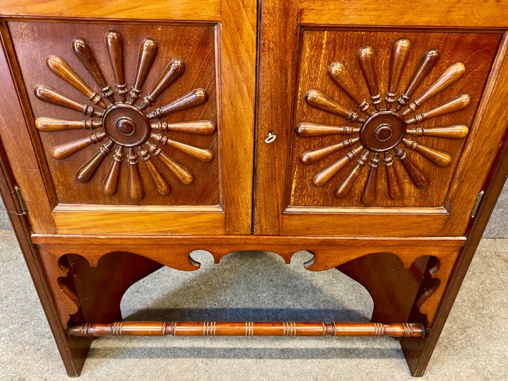 A late nineteenth-century Anglo-Moorish tiered wooden corner cabinet featuring mashrabiya fretwork, horseshoe arches, starburst door panels, and two drawers with brass pulls. View VI