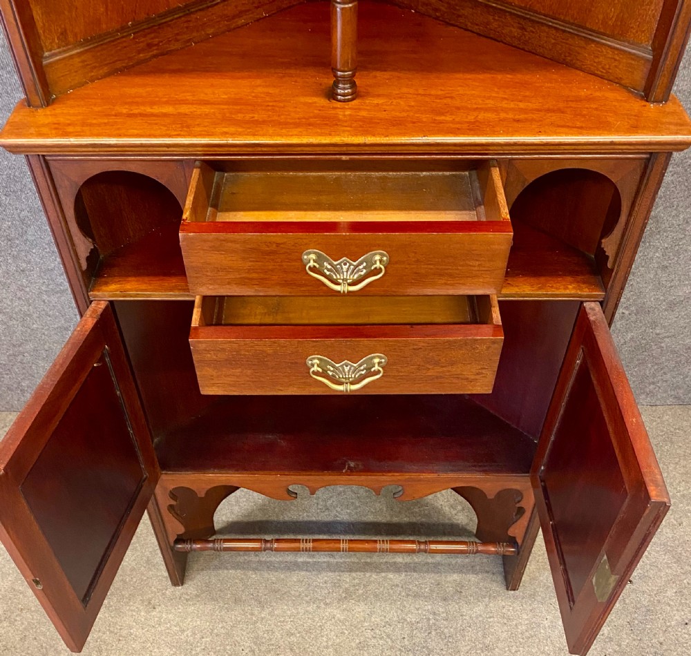A late nineteenth-century Anglo-Moorish tiered wooden corner cabinet featuring mashrabiya fretwork, horseshoe arches, starburst door panels, and two drawers with brass pulls. View VIII