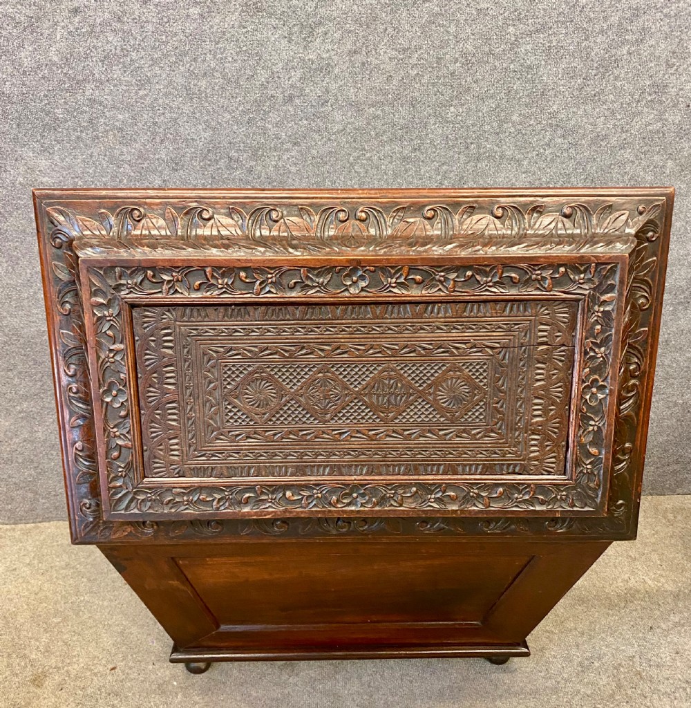 A dark hardwood Anglo-Indian carved cellarette featuring detailed floral latticework, a sarcophagus lid, and small ball feet. View III