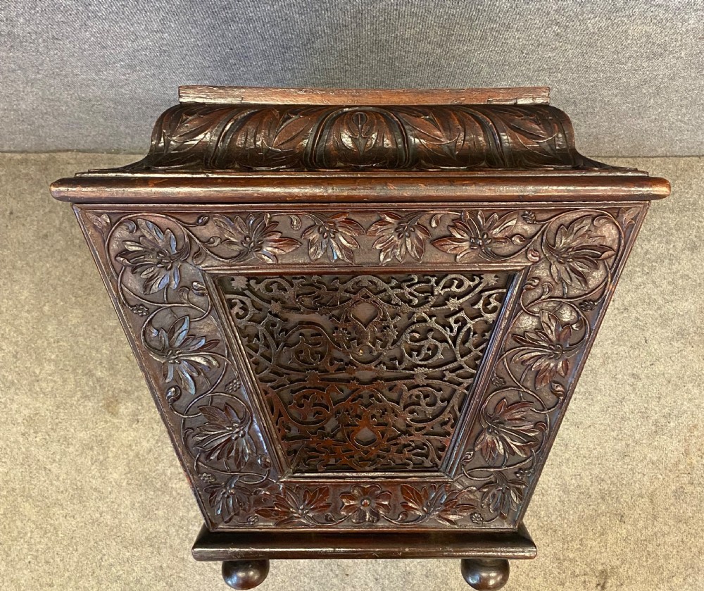 A dark hardwood Anglo-Indian carved cellarette featuring detailed floral latticework, a sarcophagus lid, and small ball feet. View IV