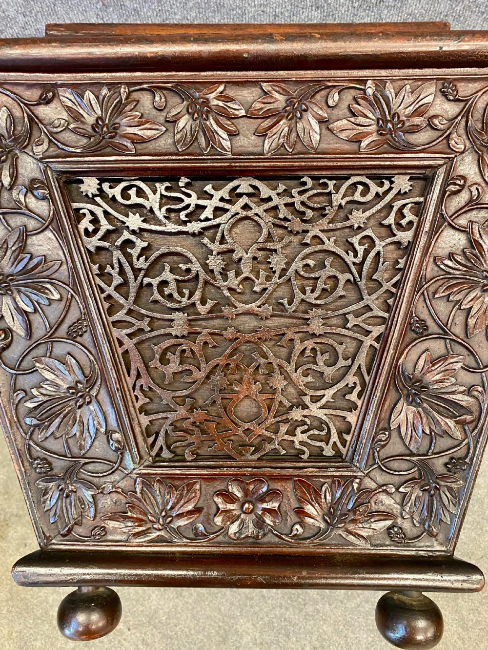 A dark hardwood Anglo-Indian carved cellarette featuring detailed floral latticework, a sarcophagus lid, and small ball feet. View V