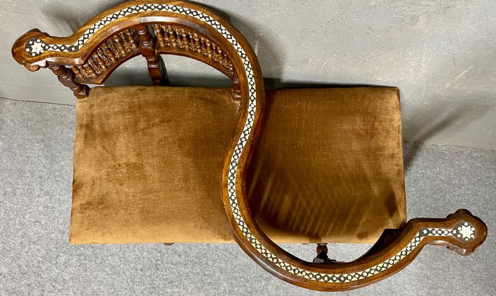 A dark hardwood Moorish Revival seating suite consisting of an S-shaped central conversation seat flanked by two corner armchairs, embellished with lathe-turned spindle lattice backs, geometric bone inlay, and mustard velvet seats. View II