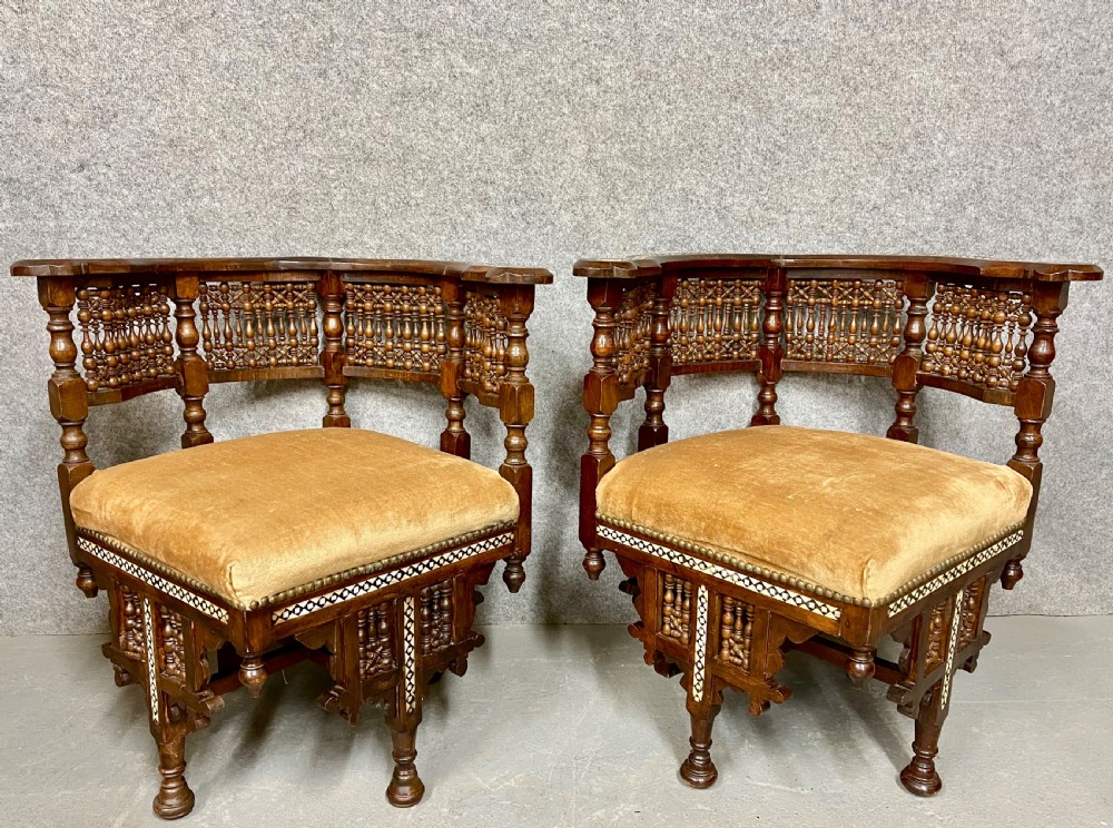 A dark hardwood Moorish Revival seating suite consisting of an S-shaped central conversation seat flanked by two corner armchairs, embellished with lathe-turned spindle lattice backs, geometric bone inlay, and mustard velvet seats. View IV