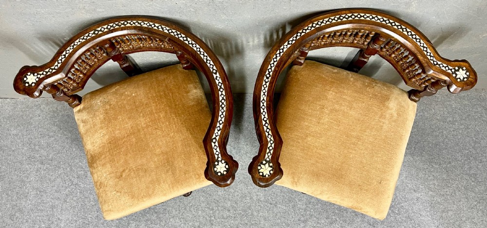 A dark hardwood Moorish Revival seating suite consisting of an S-shaped central conversation seat flanked by two corner armchairs, embellished with lathe-turned spindle lattice backs, geometric bone inlay, and mustard velvet seats. View VI