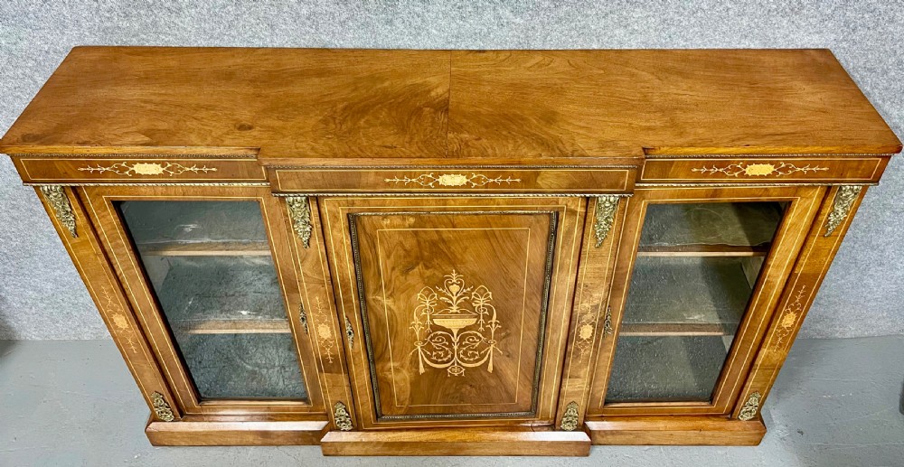 A Victorian warm brown walnut credenza featuring a central inlaid panel door flanked by two glazed display cabinet doors with gilt metal mounts. View IV