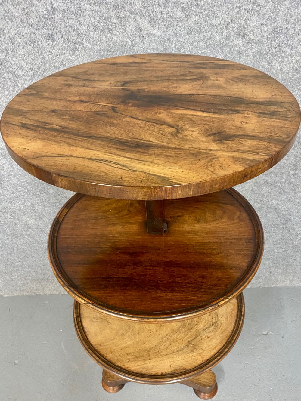 A three-tiered rosewood metamorphic table featuring circular graduated trays on a central column and a triform base with bun feet. View IV