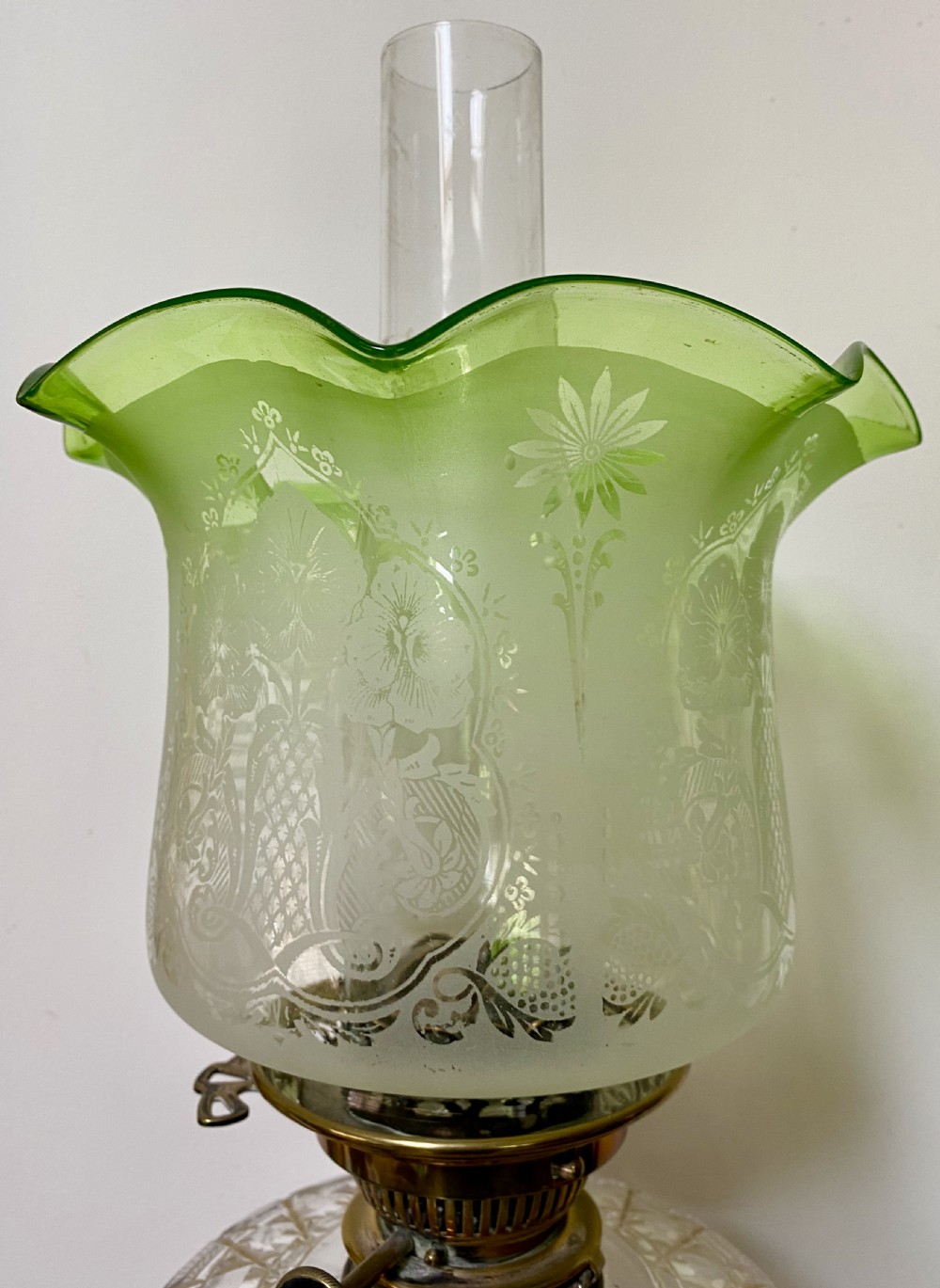 An antique ormolu oil lamp featuring a fluted Corinthian column base, a cut crystal reservoir, and an etched glass shade with a ruffled green rim. View IX