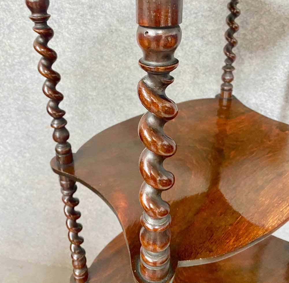 A four-tier dark rosewood whatnot featuring barley twist supports, a single base drawer, top corner finials, and brass castors. View VII
