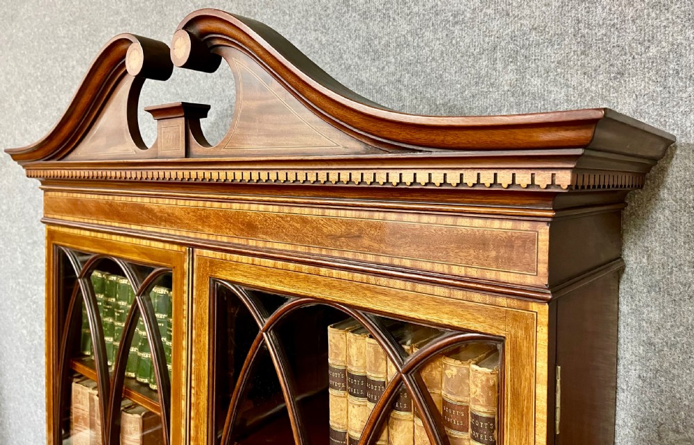 An antique mahogany Sheraton Revival bureau bookcase featuring a swan-neck pediment, astragal glazed upper doors, a slant-front writing bureau, and lower oval-panel cupboards. View VII