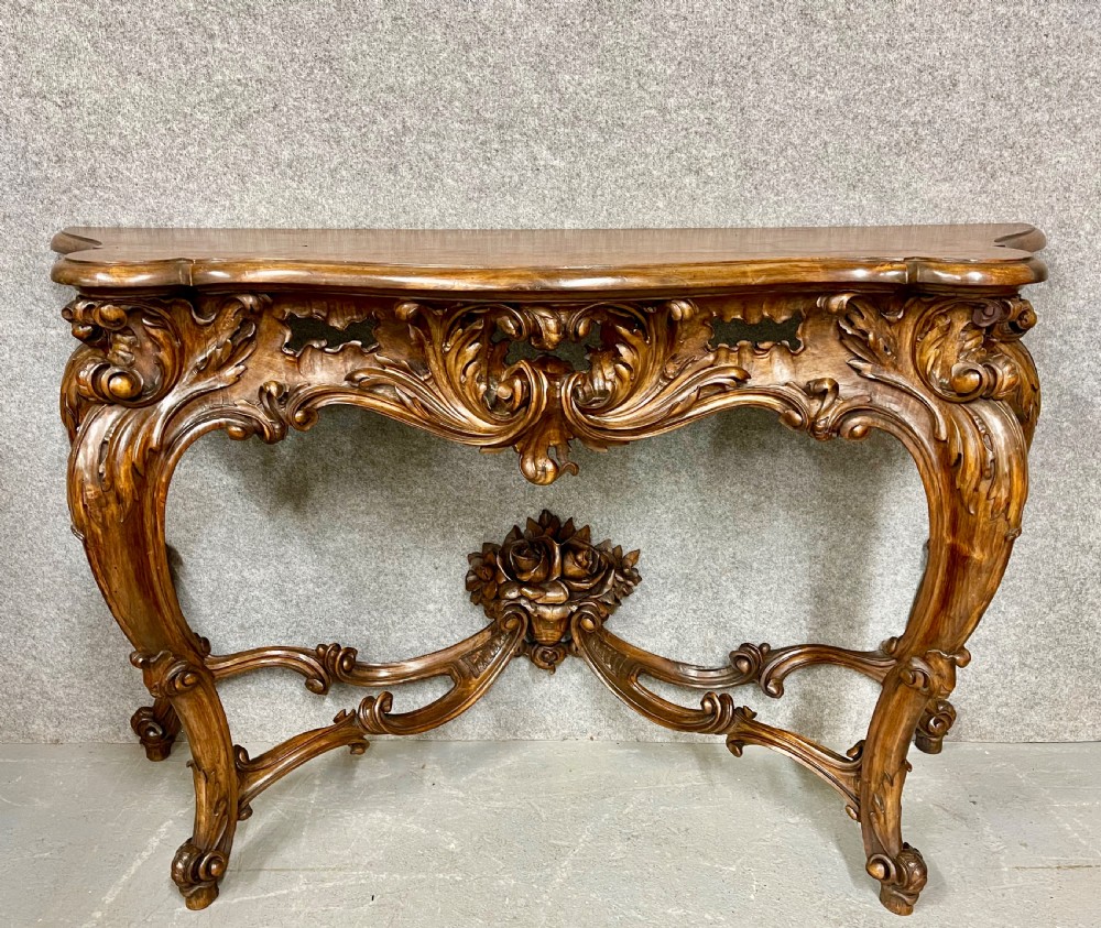 An intricately carved dark walnut console table featuring cabriole legs paired with a tall matching Rococo style arched wall mirror. View IV