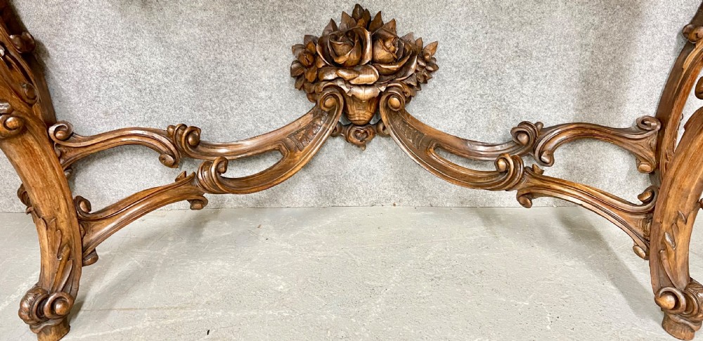 An intricately carved dark walnut console table featuring cabriole legs paired with a tall matching Rococo style arched wall mirror. View V
