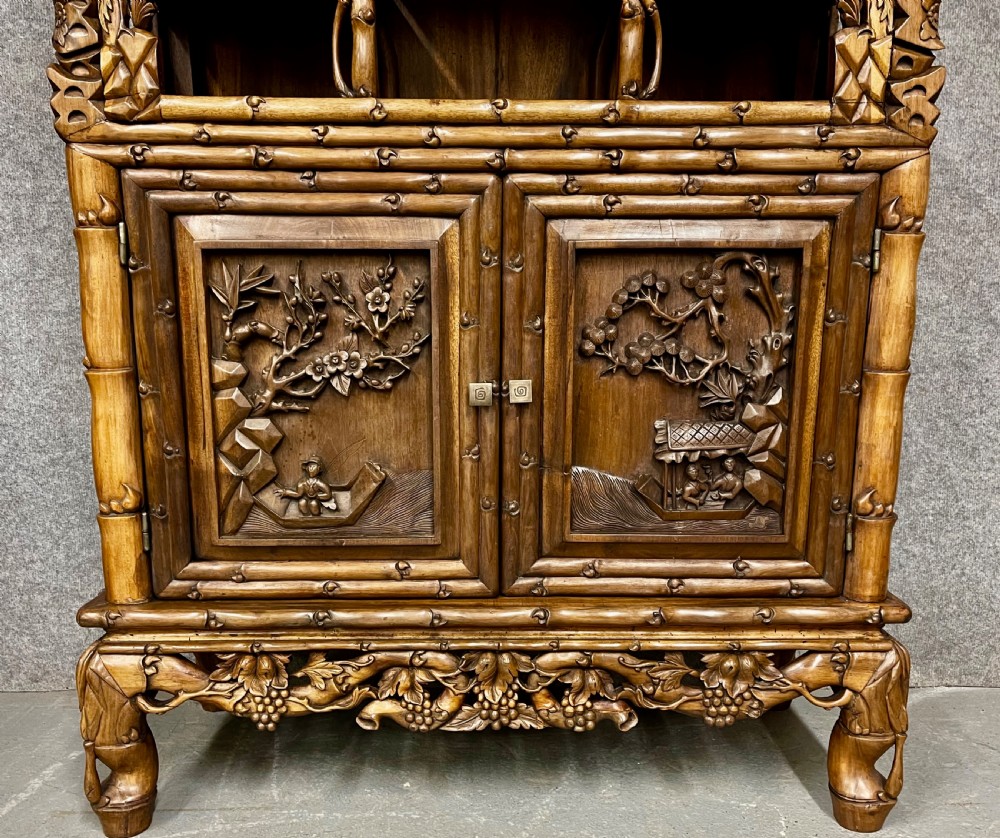 A carved Chinese hongmu open display cabinet featuring asymmetrical shelves framing intricate grapevine and bamboo motifs above a two-door base cupboard. View V